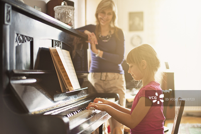 母亲看着女儿弹钢琴图片素材