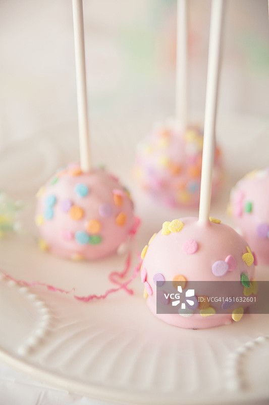 盘子里的棒棒糖蛋糕和彩色纸屑图片素材