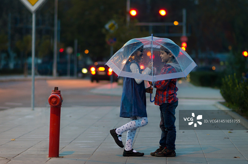 夜色城市中，男孩和女孩撑伞漫步图片素材