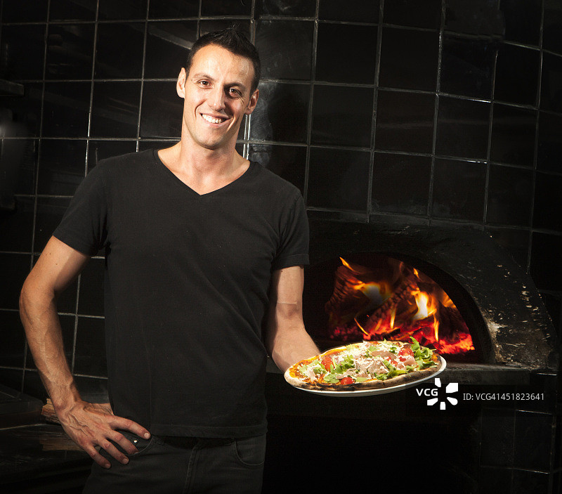 手持木烤披萨的披萨厨师图片素材