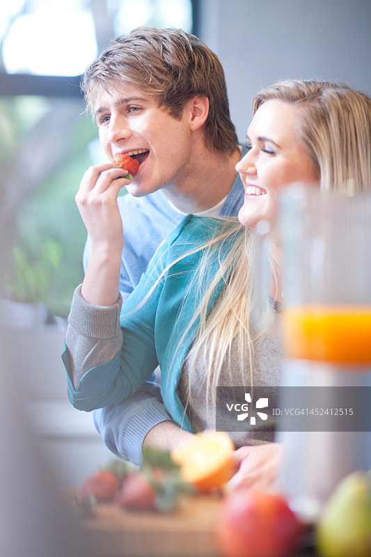 年轻夫妇吃水果和制作果汁饮品图片素材