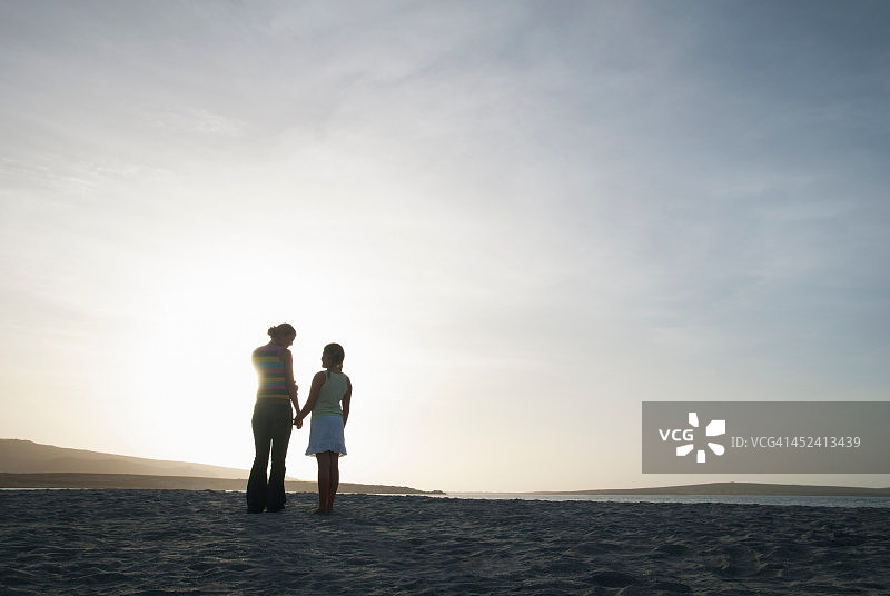 母亲和女儿在沙滩上手牵着手图片素材