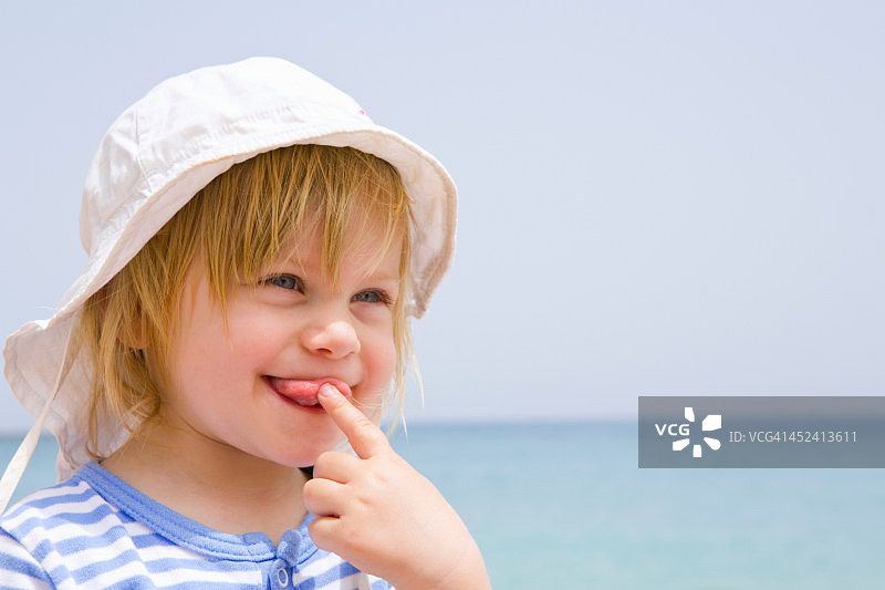 在海滩上吐舌头的婴儿肖像图片素材