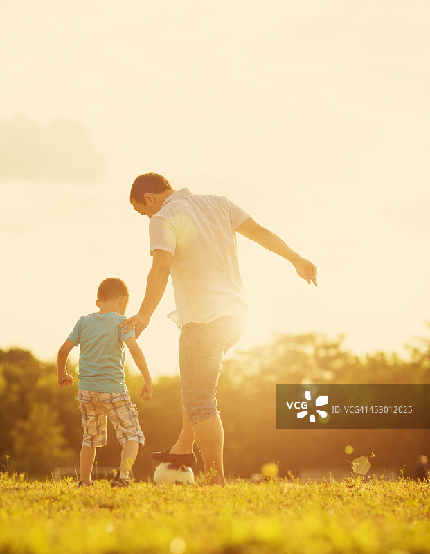 和父亲在户外踢足球的男孩图片素材