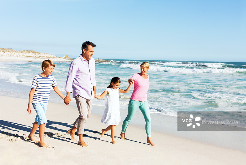 一家四口在海滩上牵手散步图片素材