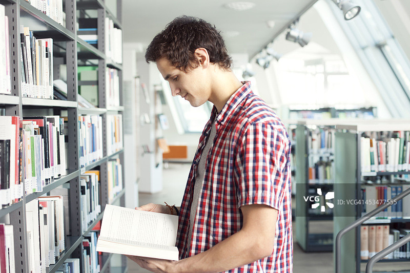 年轻男人在图书馆阅读图片素材