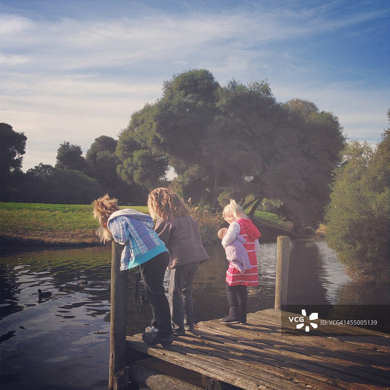 孩子们站在码头上向下看水面图片素材