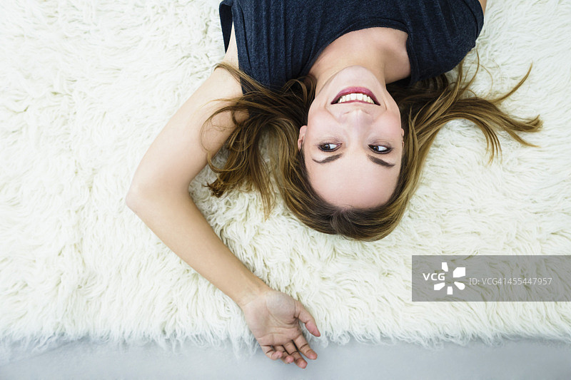 德国巴伐利亚慕尼黑：年轻女子躺在毛毯上微笑图片素材