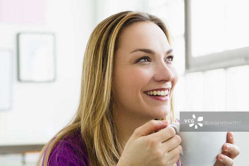 德国慕尼黑年轻女人手持茶杯微笑图片素材