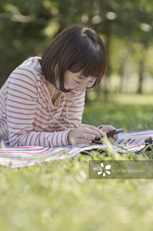 女人在绿地使用智能手机图片素材
