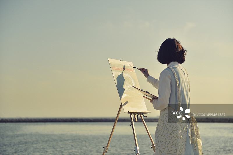 女人在海滩上画油画图片素材
