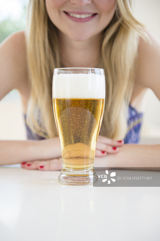 女人在啤酒杯后微笑图片素材
