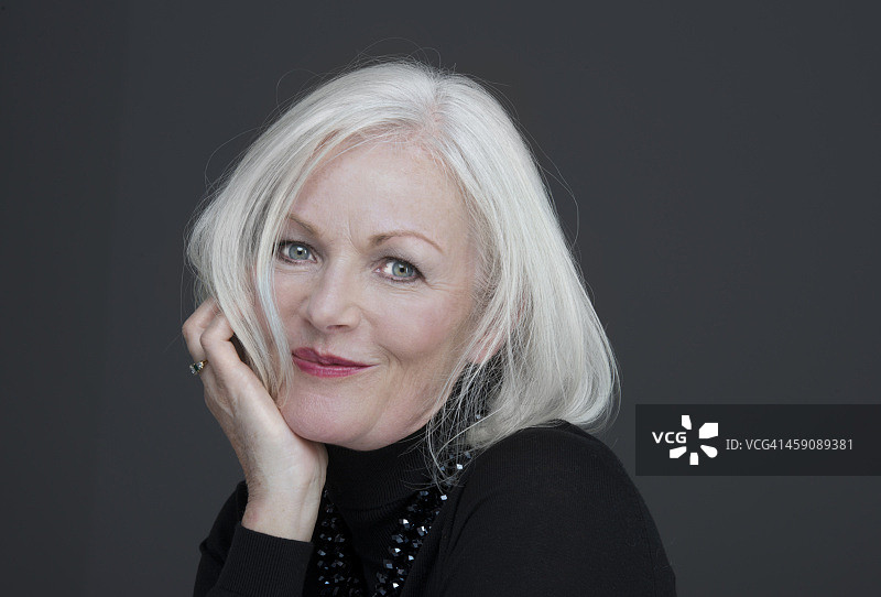 拿着头发的迷人中年妇女图片素材