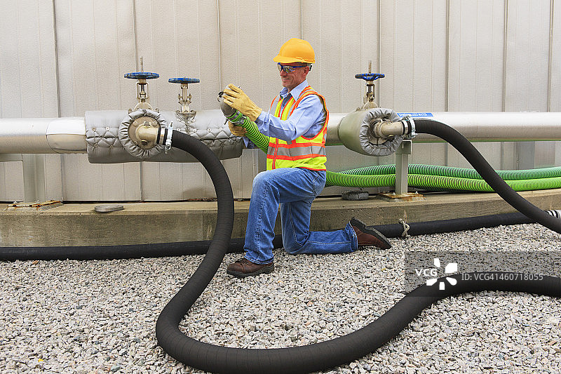 电力工程师检查储水罐附近的连接软管图片素材