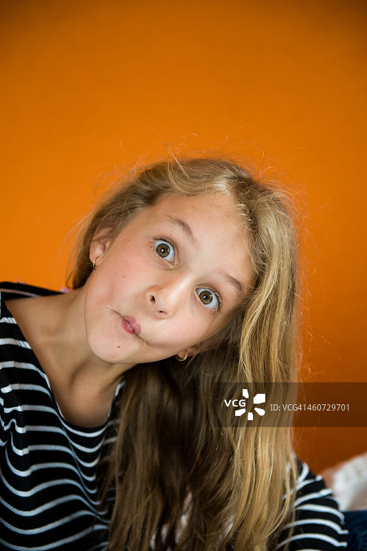 女孩在橙色背景下做鱼脸图片素材