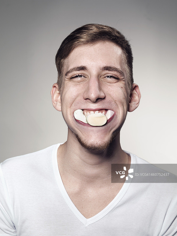 嘴里塞满棉花糖和糖果的年轻男子肖像图片素材