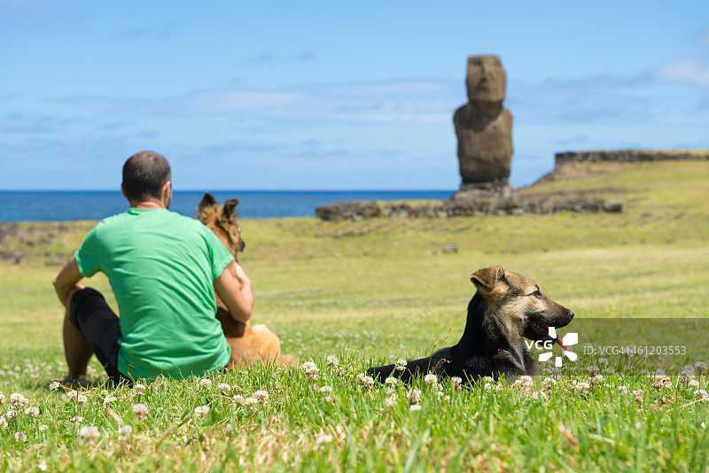 男人和狗在阿胡塔海摩艾石像享受假期图片素材