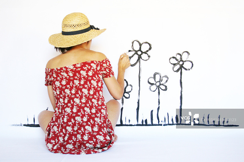 女孩在白色墙壁上画花图片素材