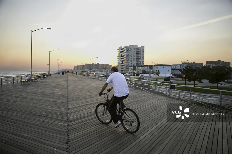 在洛克威海滩木板路上骑自行车图片素材