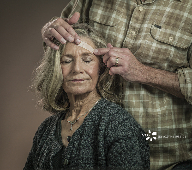 老年夫妇用药膏贴头部伤口图片素材