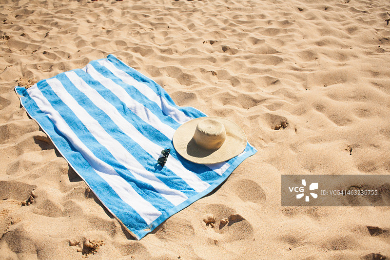 沙滩上带帽子眼镜的条纹沙滩巾图片素材