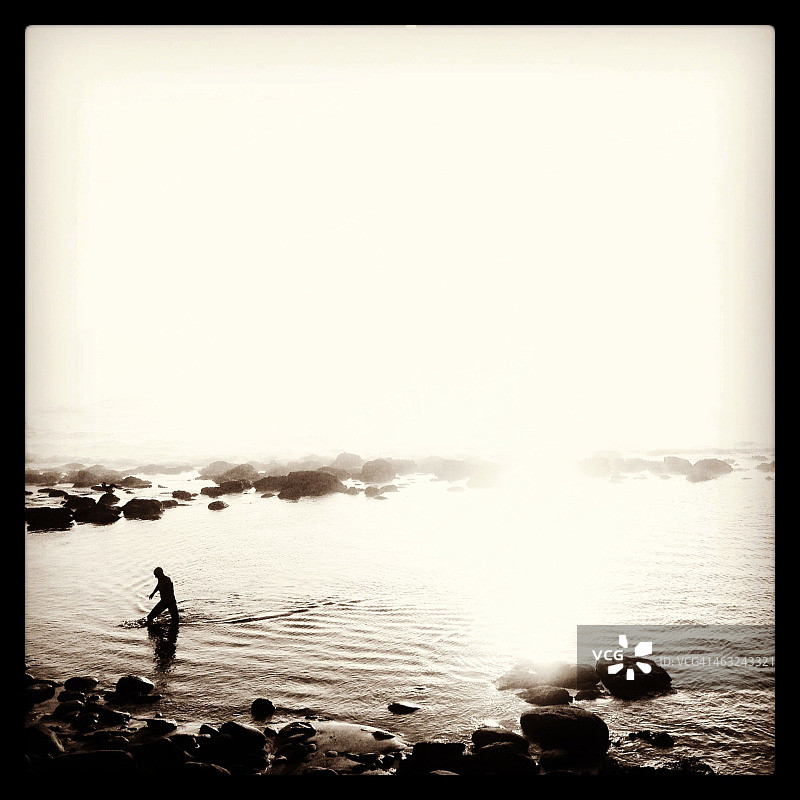 雾蒙蒙的早晨，海滩上的游泳者图片素材