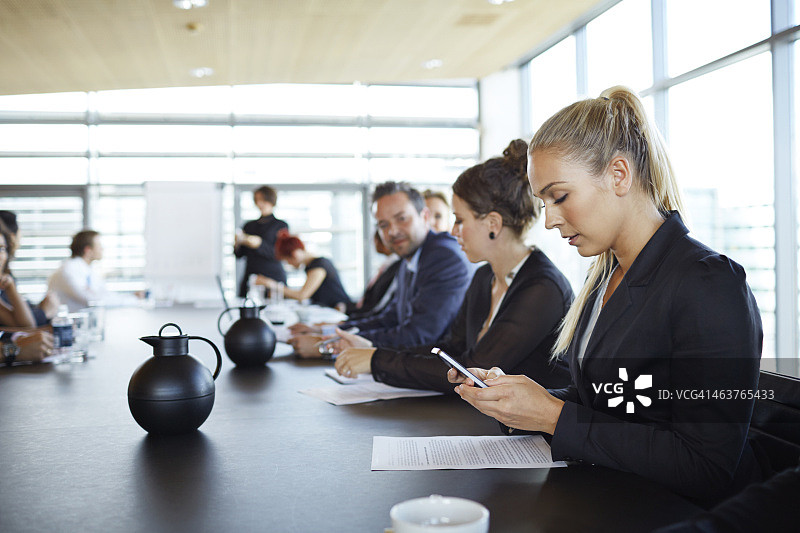 在会议上查看智能手机的女商人图片素材