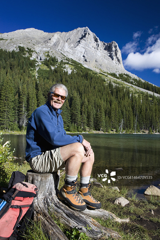 徒步者坐在山地湖泊旁的树桩上（卡纳纳斯基斯省立公园）图片素材