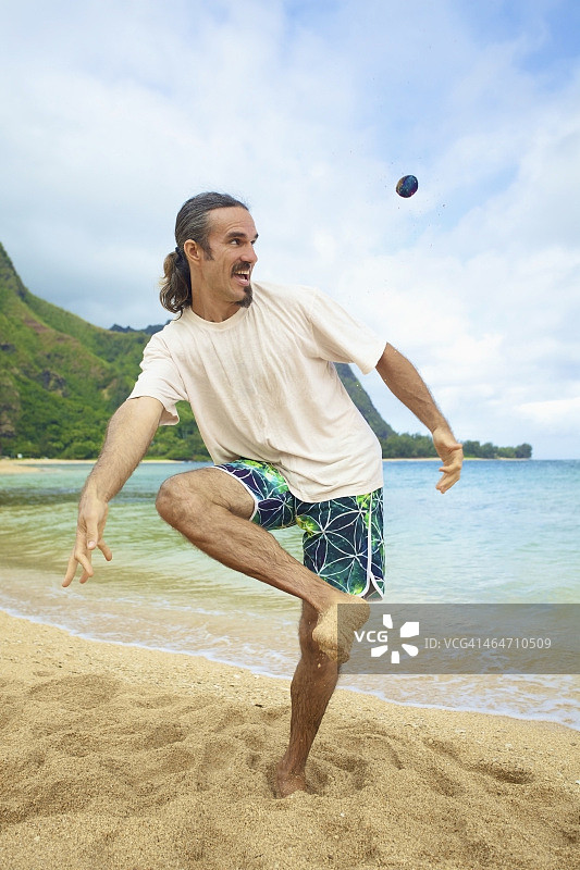 男人在水边的沙滩上玩毽子图片素材
