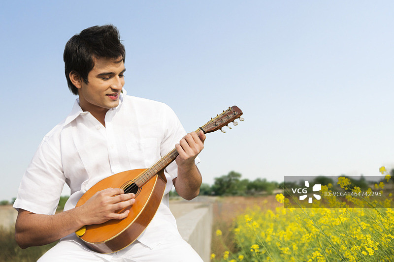 男子微笑地弹着曼陀林图片素材