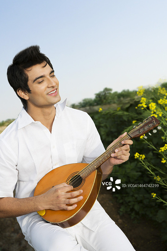 男子微笑地弹着曼陀林图片素材