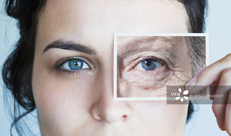 年轻女人拿着一张老年眼睛的照片图片素材