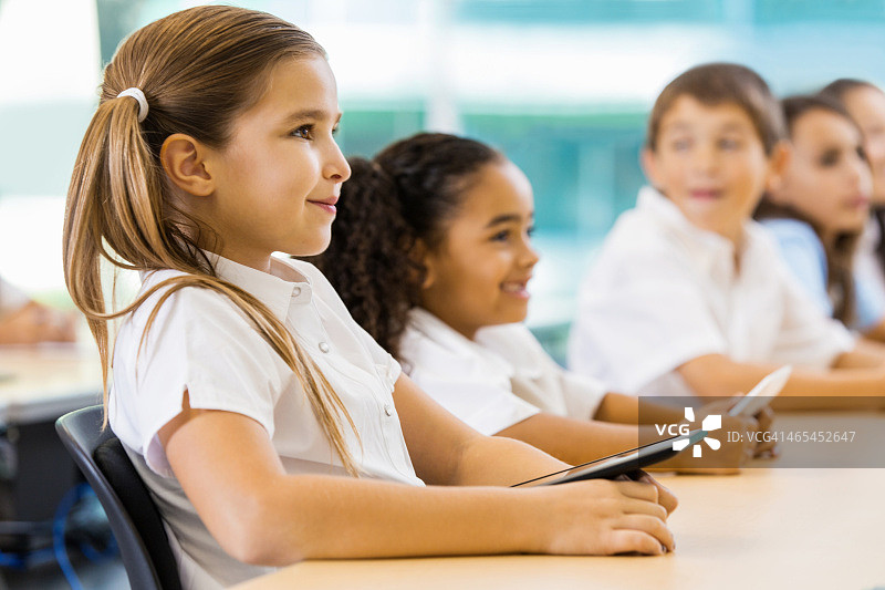 在教室里使用科技产品的快乐私立学校学生图片素材