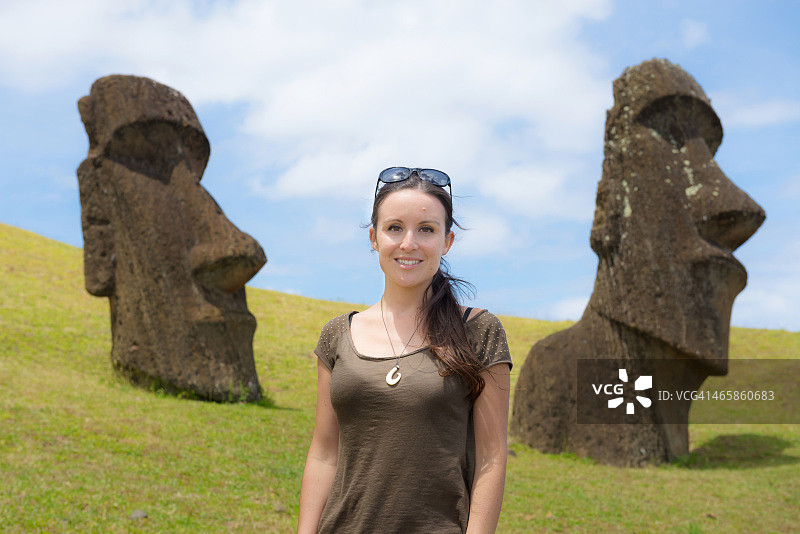 站在两尊摩艾石像旁的美丽旅行者图片素材
