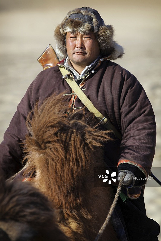 戈壁沙漠骑着双峰骆驼的游牧牧民图片素材