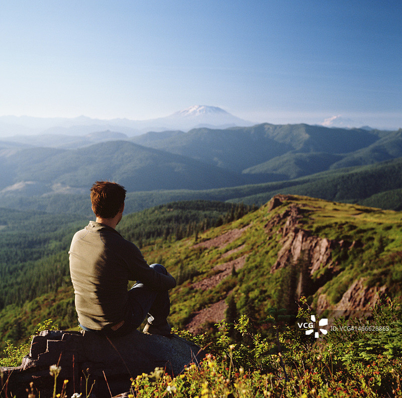 坐在悬崖边俯瞰群山的男人图片素材
