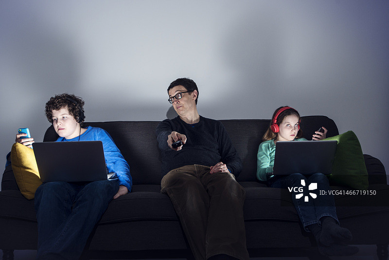 父亲和孩子们在沙发上使用科技产品图片素材