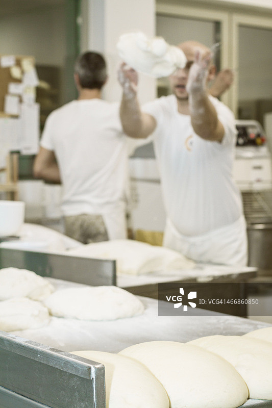 面包师在工作台上抛撒发酵面团图片素材
