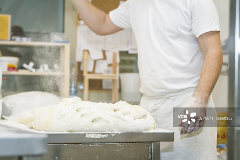 面包师在工作台上将面粉撒在发酵的面团上图片素材
