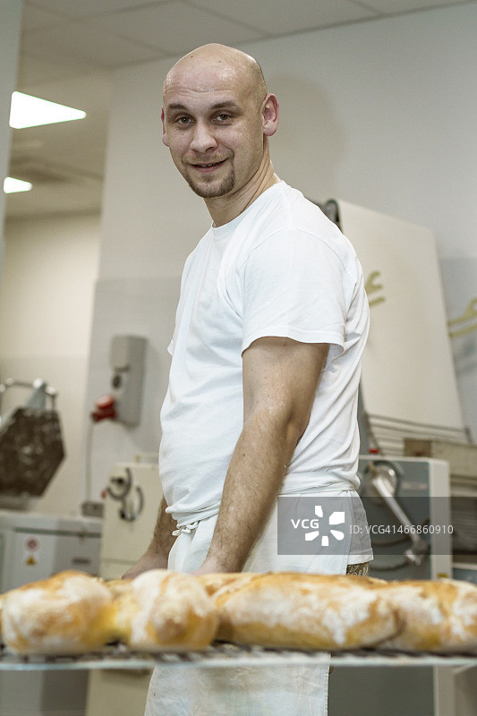 面包师用铲子拿着烤好的面包图片素材