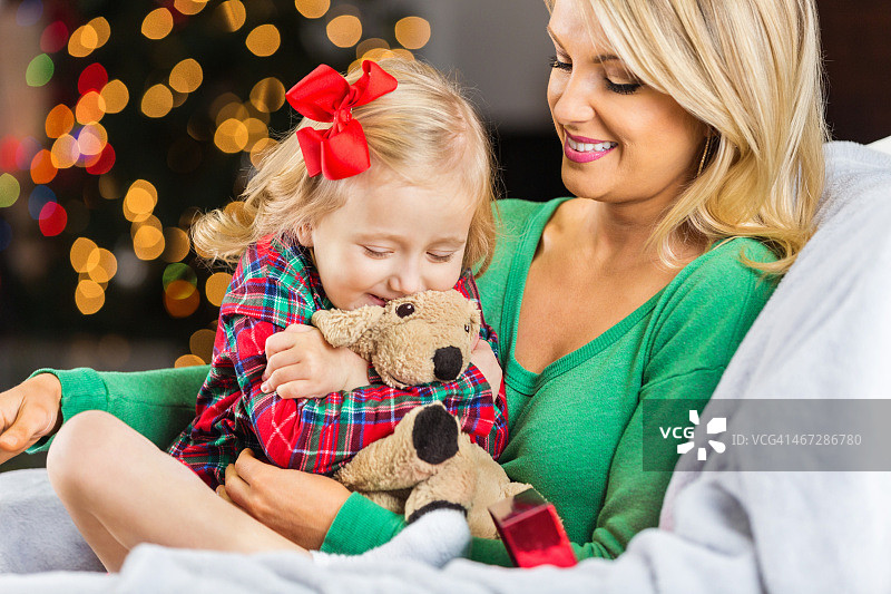 圣诞节，快乐的小女孩和妈妈拥抱毛绒动物图片素材