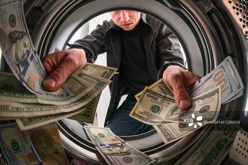 白人男罪犯在洗衣机里扔钱图片素材