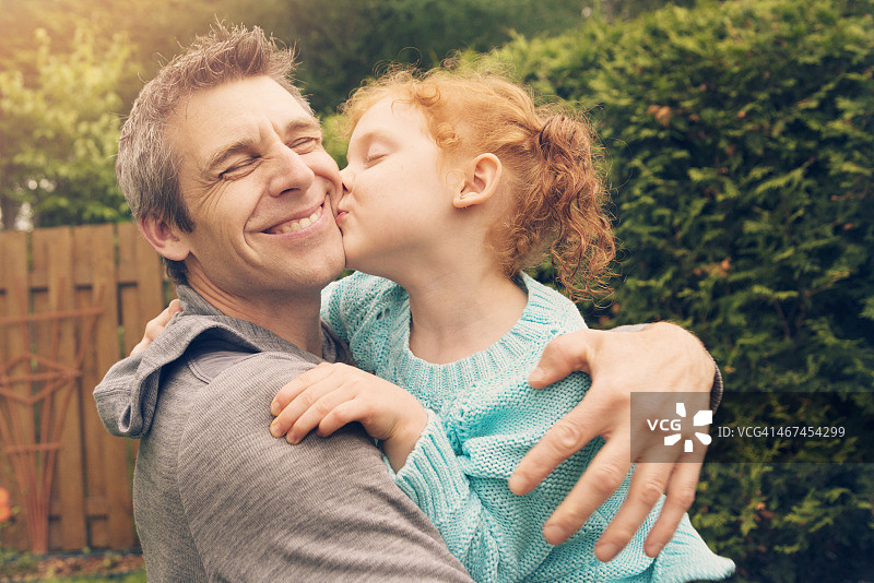 户外亲吻拥抱父亲的红发小女孩图片素材