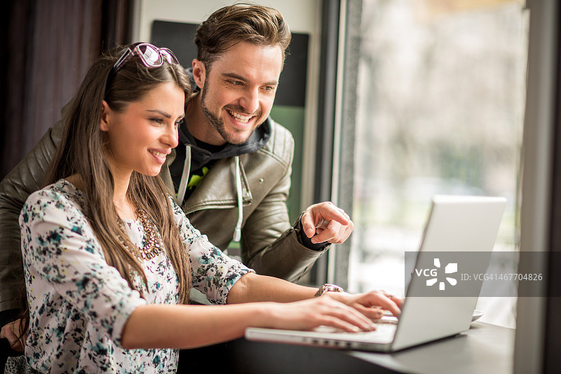 在咖啡店看笔记本电脑屏幕的情侣图片素材