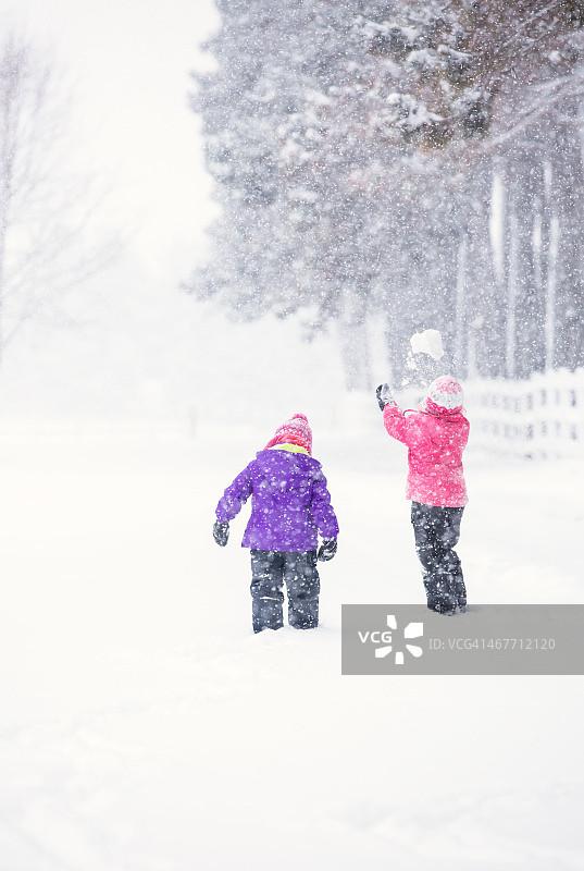 两个年轻女孩在冬季暴风雪中在户外玩耍图片素材