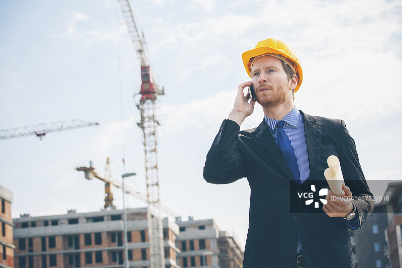 工程师使用智能手机交谈并手持蓝图图片素材