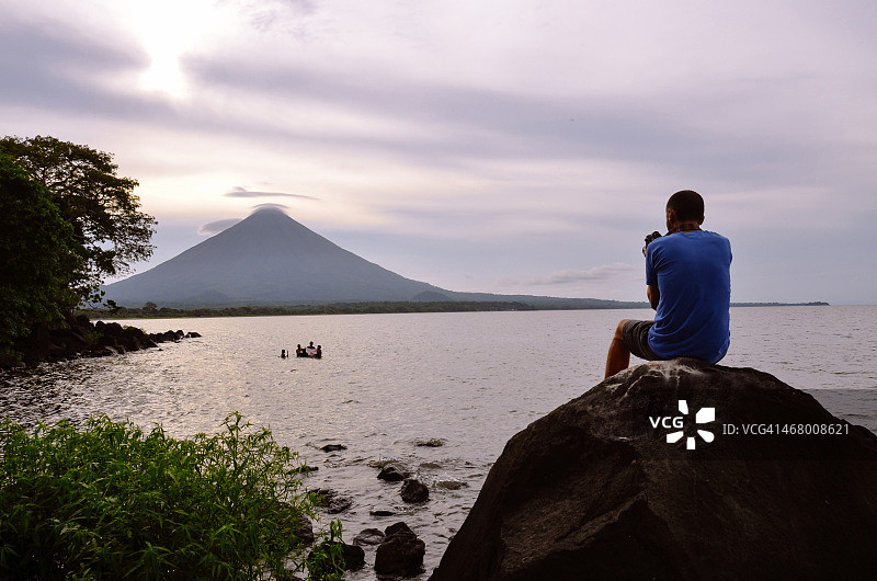 男子坐在岩石上看火山日落图片素材