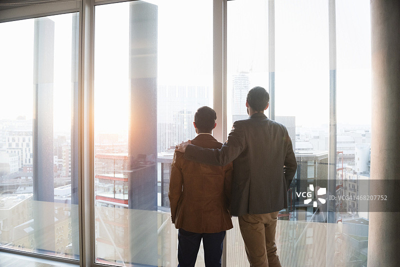 两个男人隔着窗户欣赏城市图片素材