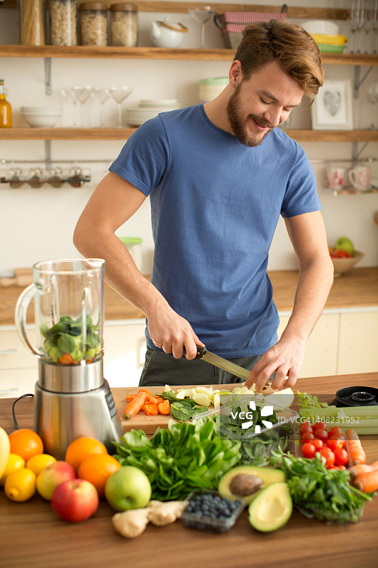 年轻男人在厨房制作果汁或冰沙图片素材