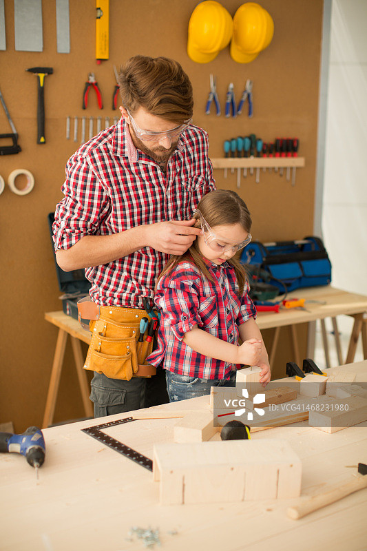 在木工房里和可爱的小女儿在一起的父亲图片素材